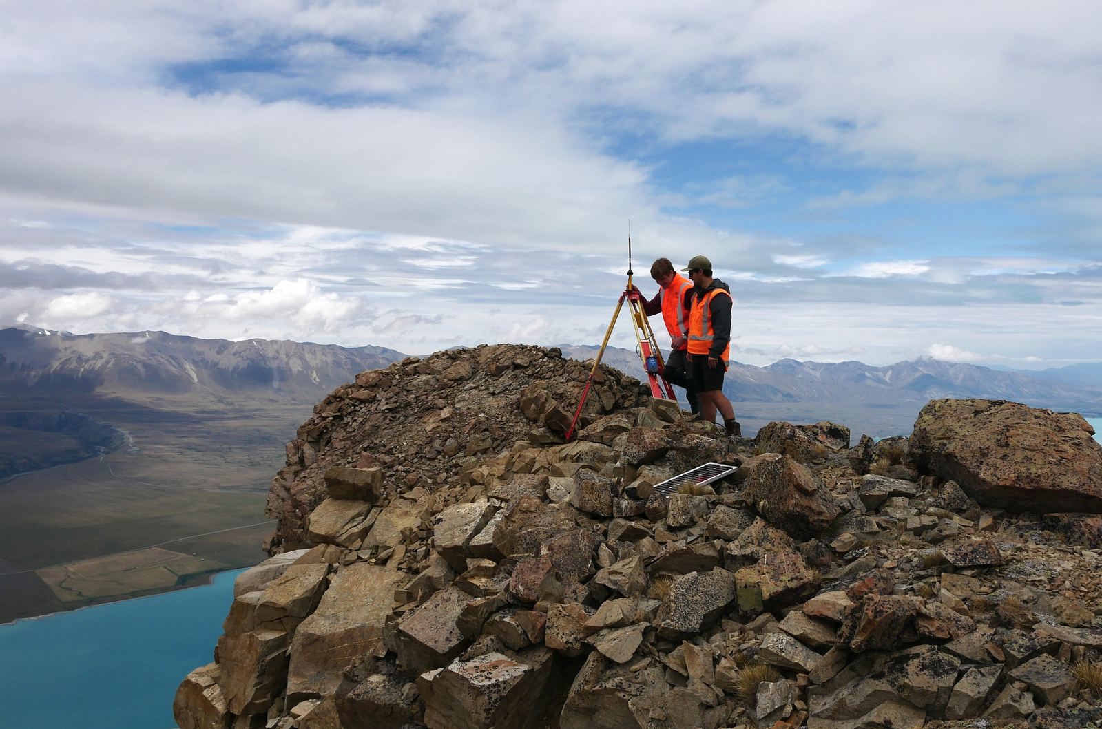 Surveying equipment set up on a high-country peak above an alpine lake