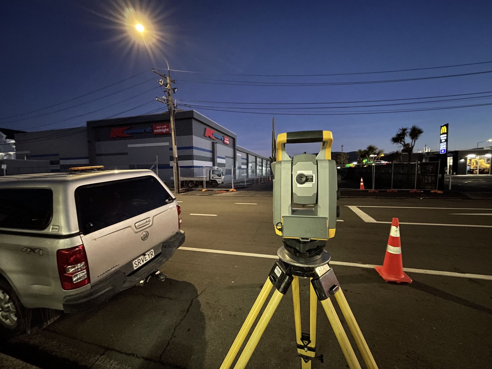 A total station set up at a commercial site after dark